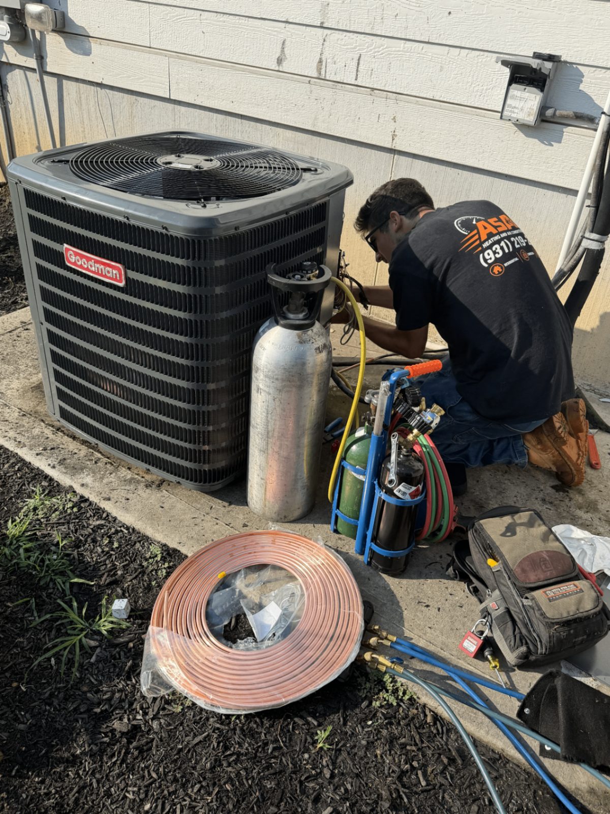 ASAP Heating and Air-Conditioning LLC technician brazing a copper line set with nitrogen purge on a Goodman outdoor condenser during an air conditioning installation in Centerville, Tennessee.