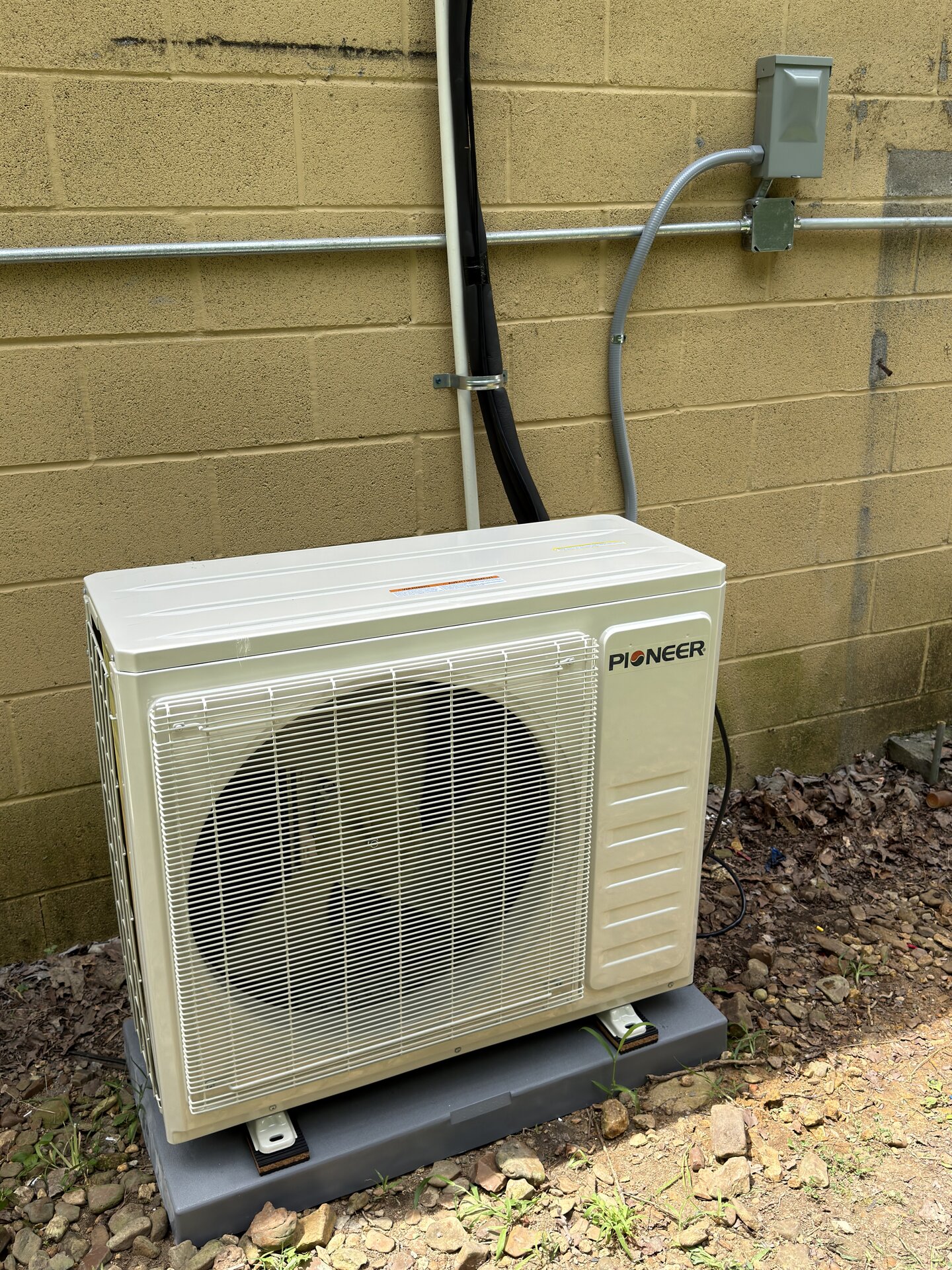 Newly installed Pioneer ductless mini split outdoor condenser mounted on a pad with disconnect and line set by ASAP Heating and Air-Conditioning in Middle Tennessee.
